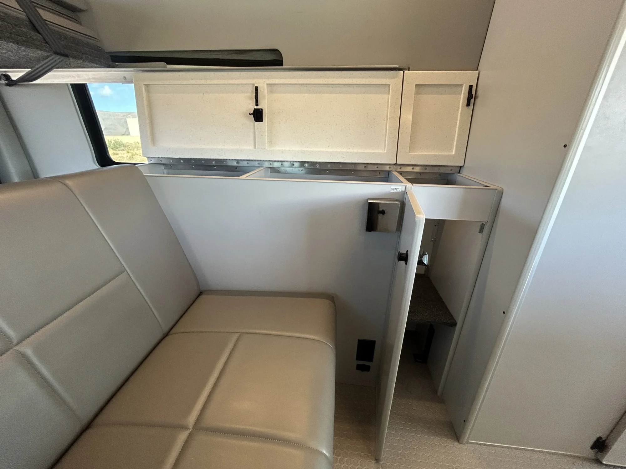 2024 Ford Transit 350 148 High Roof AWD, driver-side overhead cabinets, rear sofa, and open storage locker