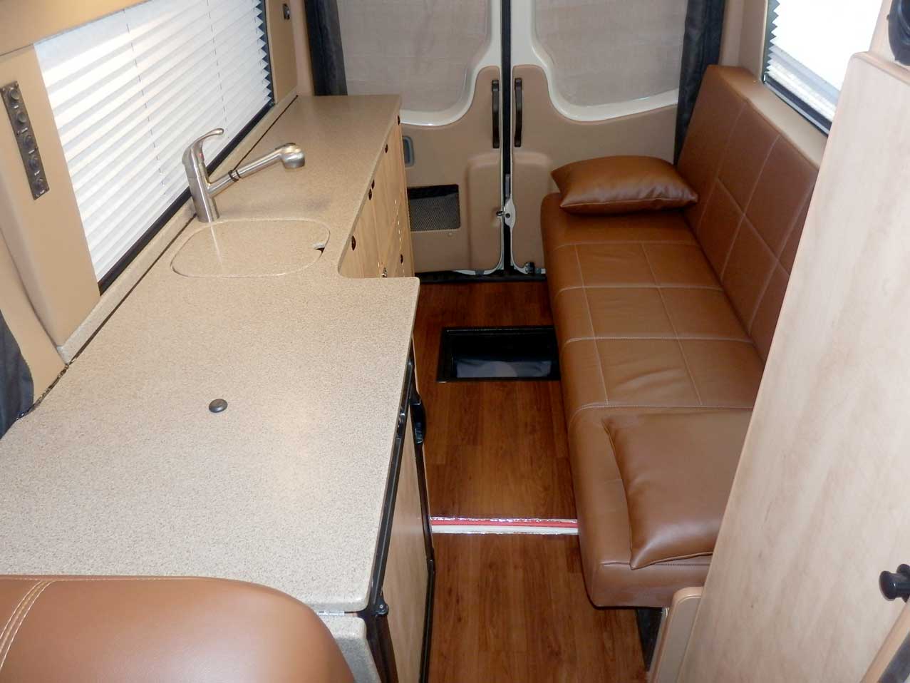 Transit van conversion with upgraded leather upholstery and custom cabinets.