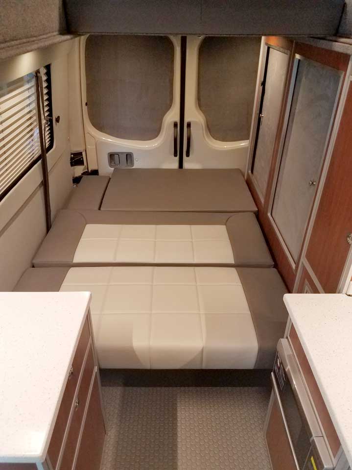 An interior bed inside a custom Sportsmobile Sprinter RB 150M conversion van.