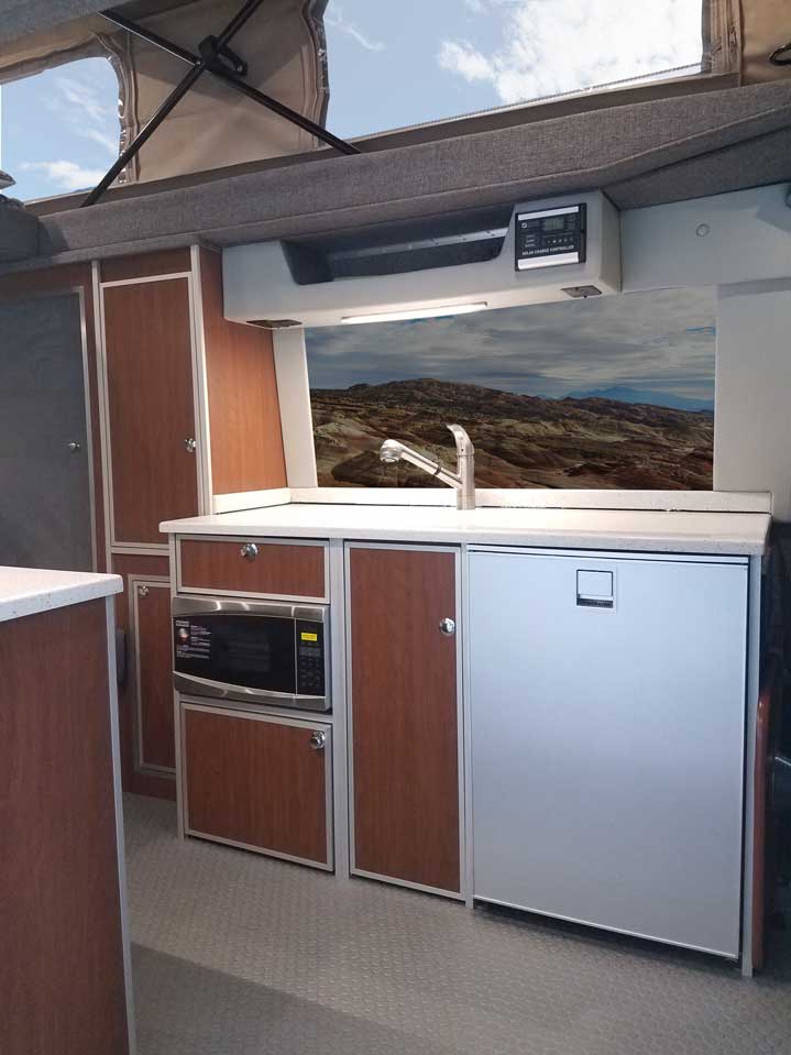 Porta Pottie stows under microwave inside a custom Sportsmobile Sprinter RB 150M conversion van.