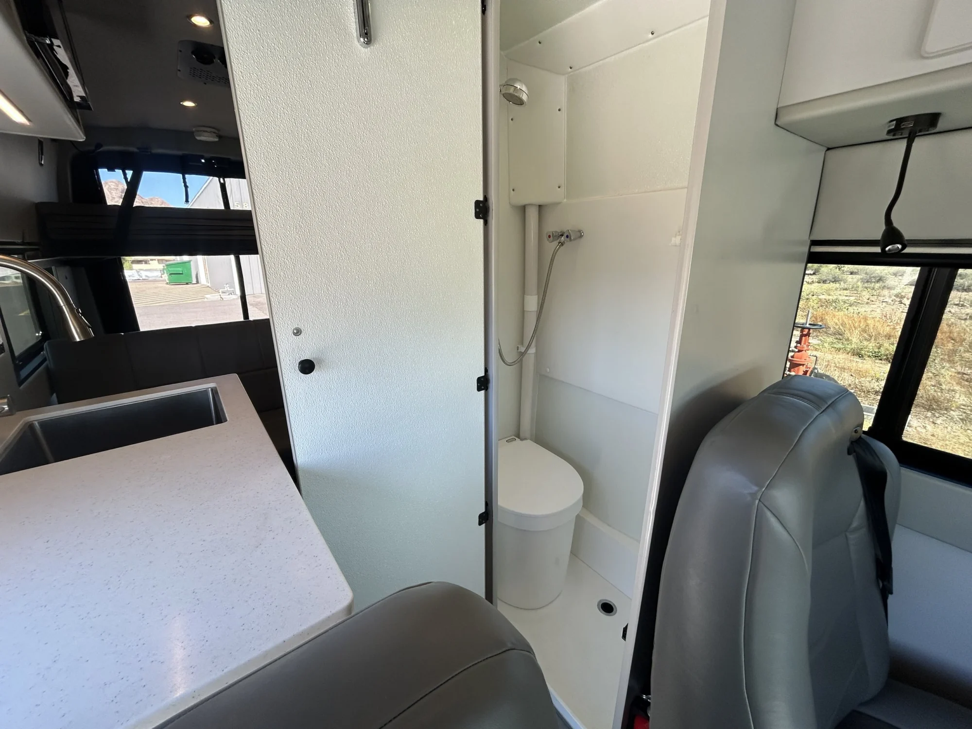 2024 Ford Transit 350 148 High Roof AWD, tall bath compartment with door open showing shower wand, Brisk pan, and Separette toilet