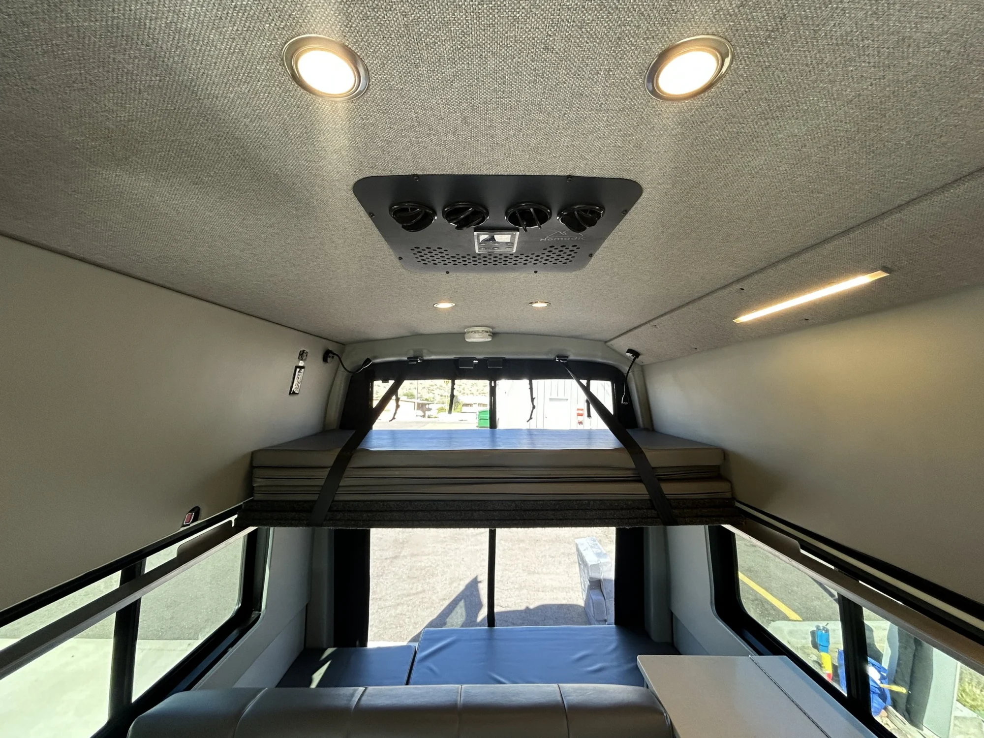 2024 Ford Transit 350 148 High Roof AWD, ceiling view with Nomadic 12V roof-top A/C, LED puck lights, and upper platform bed