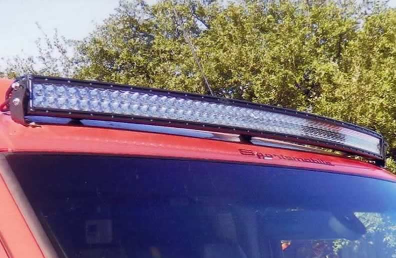 A custom red Sportsmobile conversion van with an upgraded exterior LED light bar.