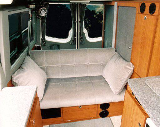 Interior view of a sofa that seats 4 inside of camper van.