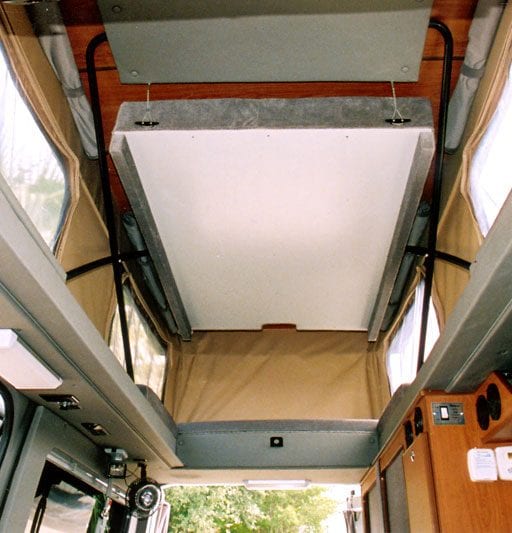 Interior view of bed connected to penthouse top inside of camper van.