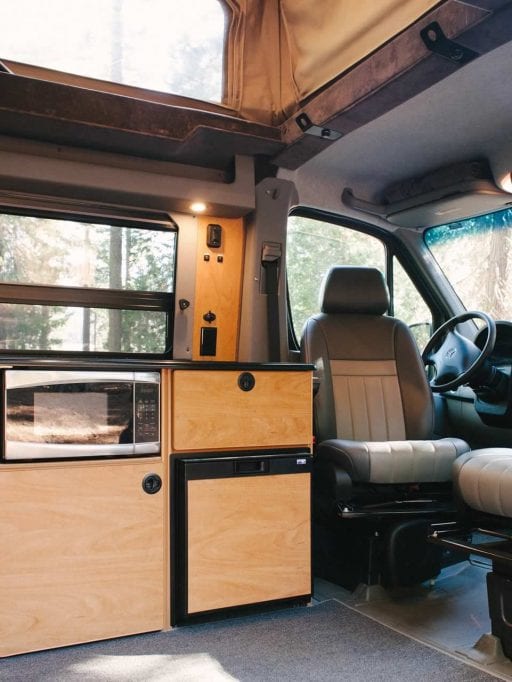 Interior view of Sportsmobile camper van converison with wood cabinets in the galley.
