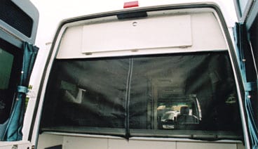 A white custom Sportsmobile van conversion with partial rear door screens installed.