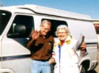 Sportsmobile owners, the Parsons, stands next to his custom white conversion van.