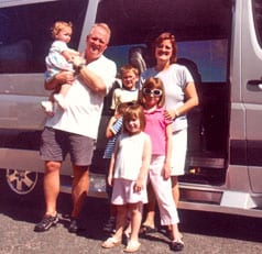 The whole family poses next to their Sportsmobile Sprinter van conversion.