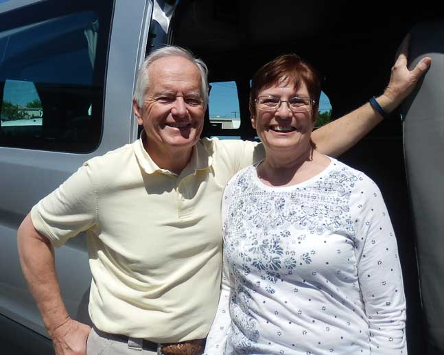 Pleased Sportsmobile owners, Tom and Debra, with big smiles next to their custom conversion van.
