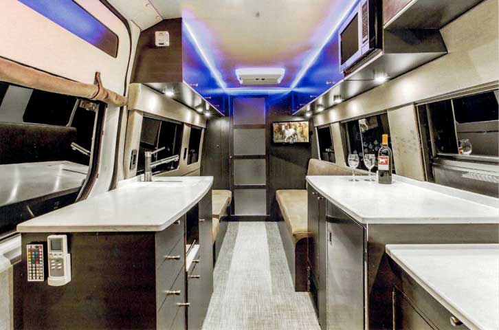 Interior view of a custom Sportsmobile van conversion featuring a kitchen and sleeping area.
