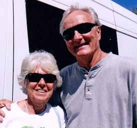David and Julia Olsen stand proudly next to their white Sportsmobile custom conversion van.