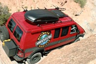 Red 4x4 Sportsmobile conversion traveling through tight spots in the Moab.