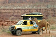 Sportsmobile with a camel companion in the Moab desert.