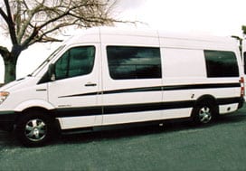 Profile view of a white Sportsmobile van conversion with two large fixed windows.