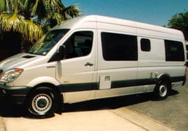 Profile view of a silver Sportsmobile van conversion with a slider window for the bath.