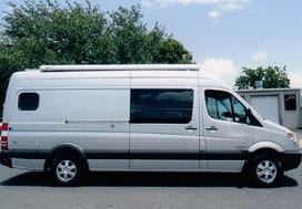 Profile view of a white Sportsmobile van conversion with a large fixed door window.