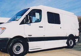 Profile view of a white Sportsmobile van conversion with an awning window.