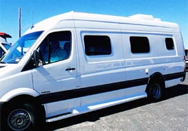 Profile view of a white Sportsmobile van conversion with an awning window and a small slider.