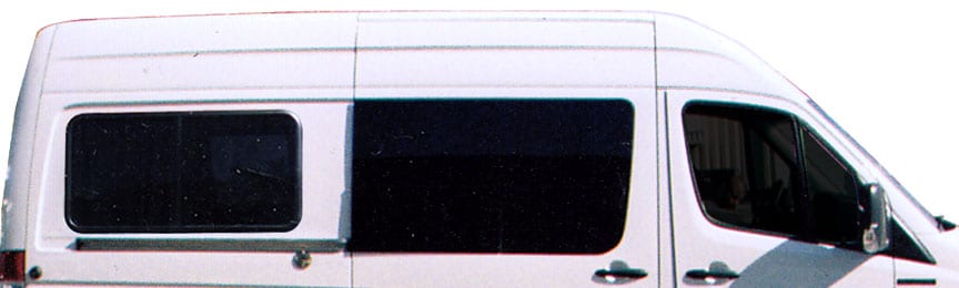 Profile view of a high roof white Sportsmobile van conversion with two large awning windows.