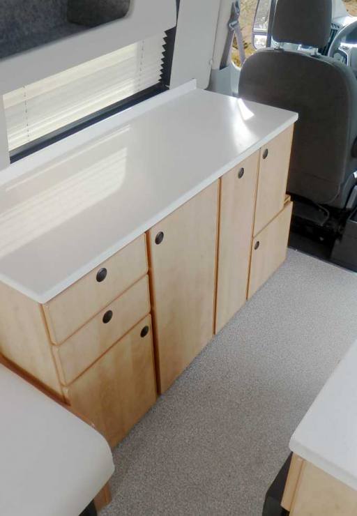 Interior Transit camper view with white cabinets.