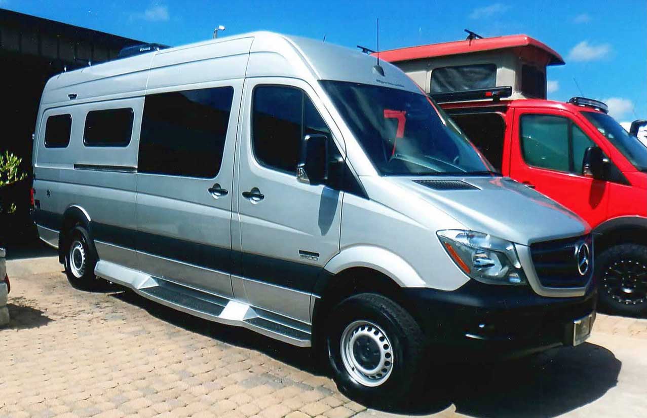 A custom silver Sportsmobile conversion van with upgraded fiberglass running boards.