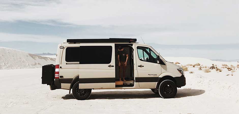 A Sportsmobile 4x4 custom camper conversion on the desert sands.
