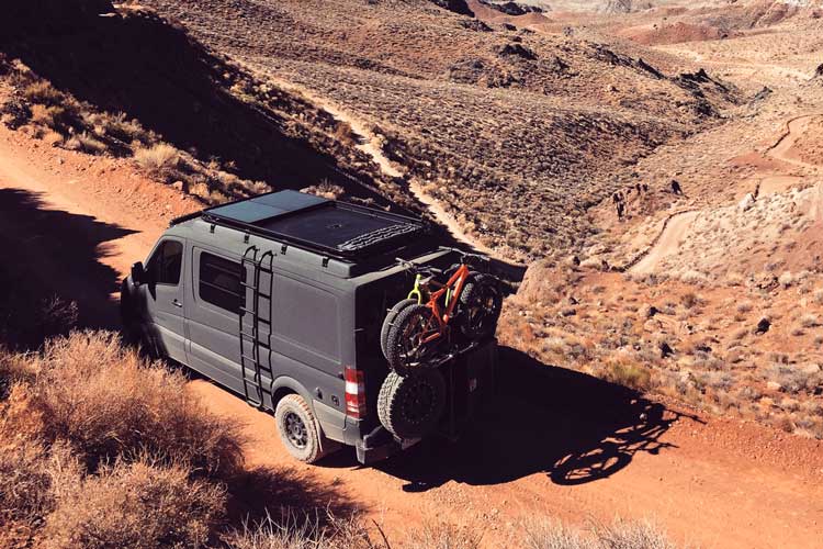 A gun metal grey Sportsmobile 4x4 custom camper van conversion traveling through the mountains.