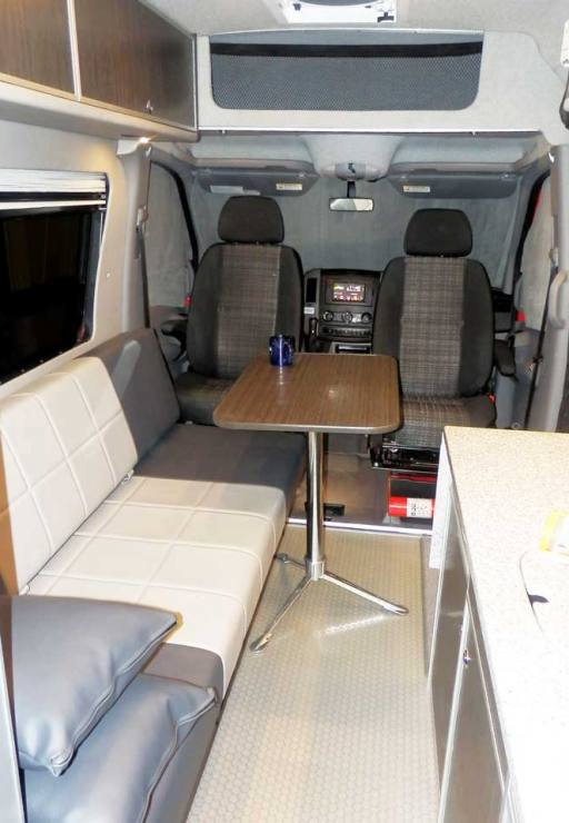 Interior view of a custom Sportsmobile Sprinter 4x4 van conversion with front seats and table.