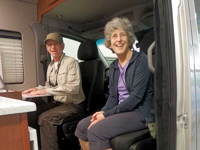 Happy Sportsmobile customers sitting in their new custom camper van conversion.