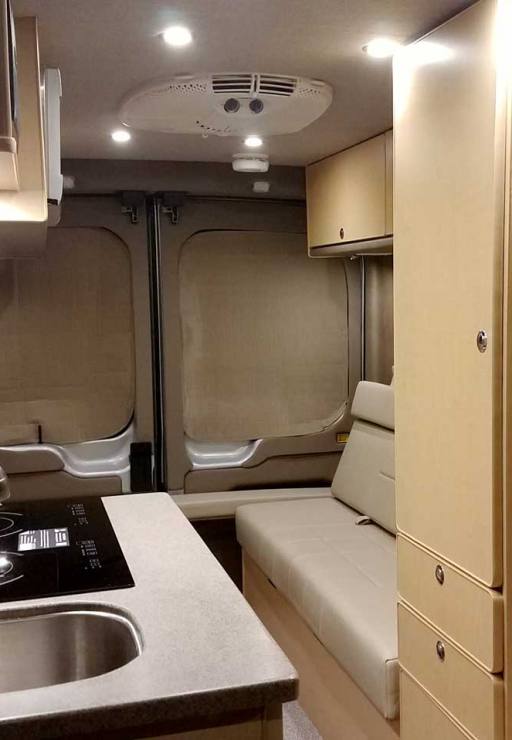 Inside a custom silver Sportsmobile Transit conversion van with dinette that seats six people.