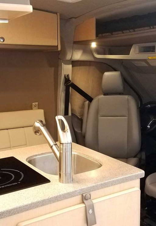 Inside a custom silver Sportsmobile Transit conversion van with a flip up counter top extension.