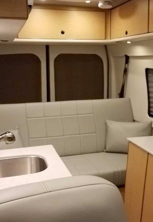 Interior view of a custom Sportsmobile Transit conversion van with rear couch with seat belts.