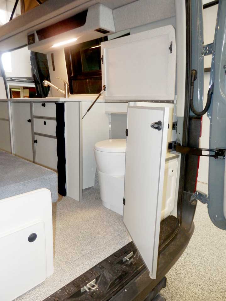 Interior view of toilet compartment next to cabinets in a Sportsmobile conversion van.