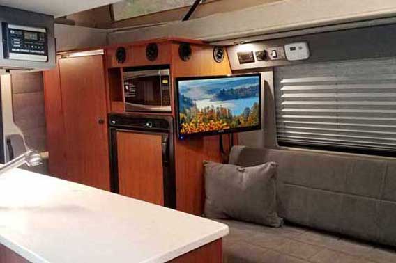 Sprinter conversion van with a TV, microwave, and galley.