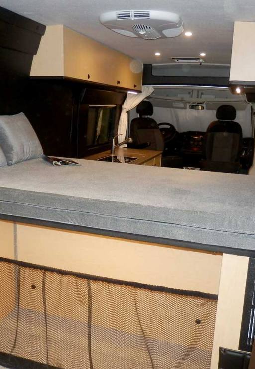 Rear view of a custom Sportsmobile Promaster conversion van featuring a platform bed with large compartments for storage.