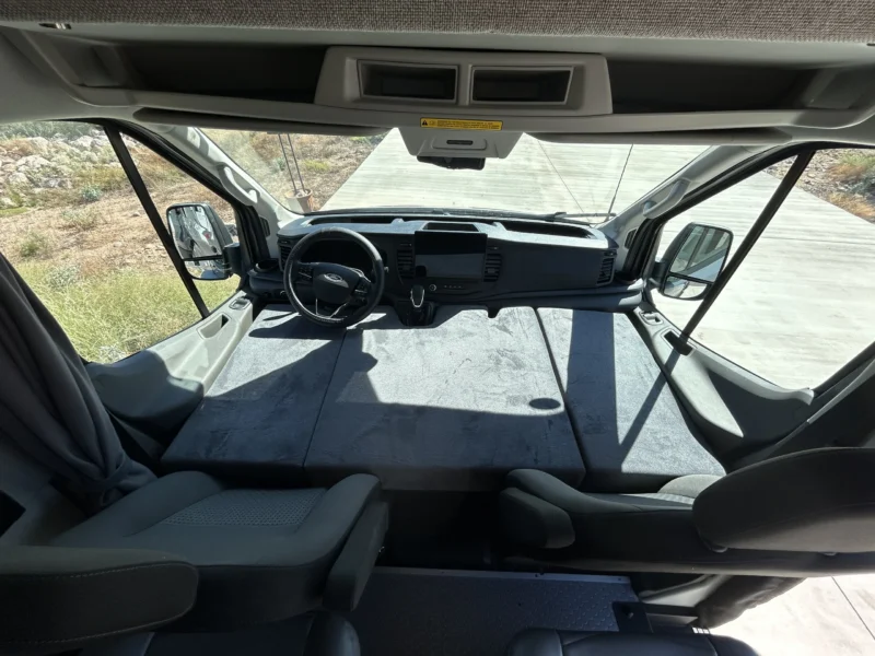 2024 Ford Transit 350 148 High Roof AWD, cab bed deployed across the front seats with rear captain's chairs swiveled