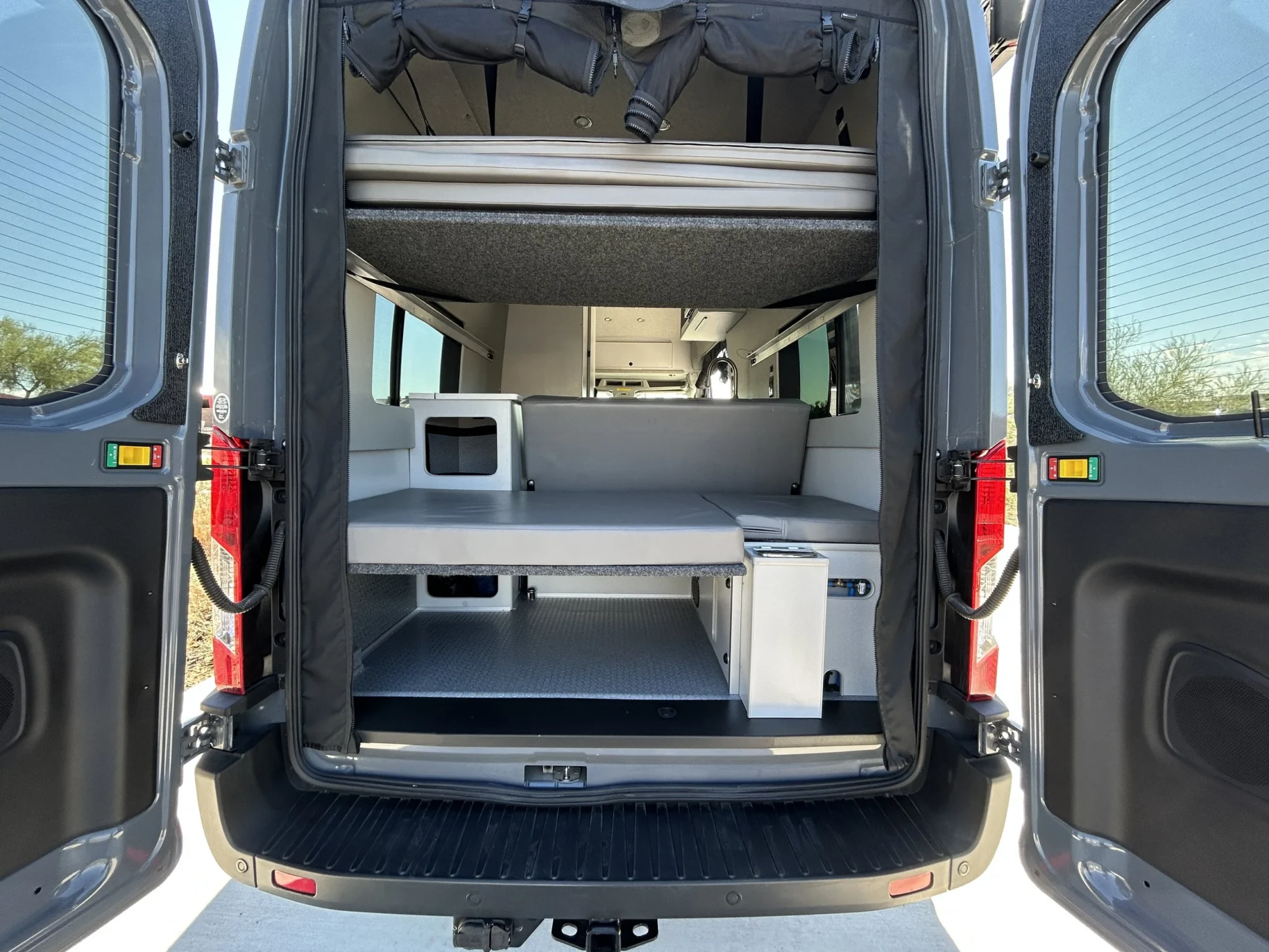 2024 Ford Transit 350 148 High Roof AWD, rear doors open showing upper platform bed, lower mattress, and under-bed garage storage