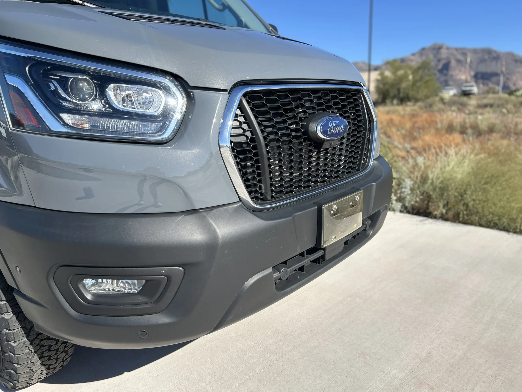 2024 Ford Transit 350 148 High Roof AWD, front passenger-side three-quarter close-up showing grille, HID headlamps, and fog lamps