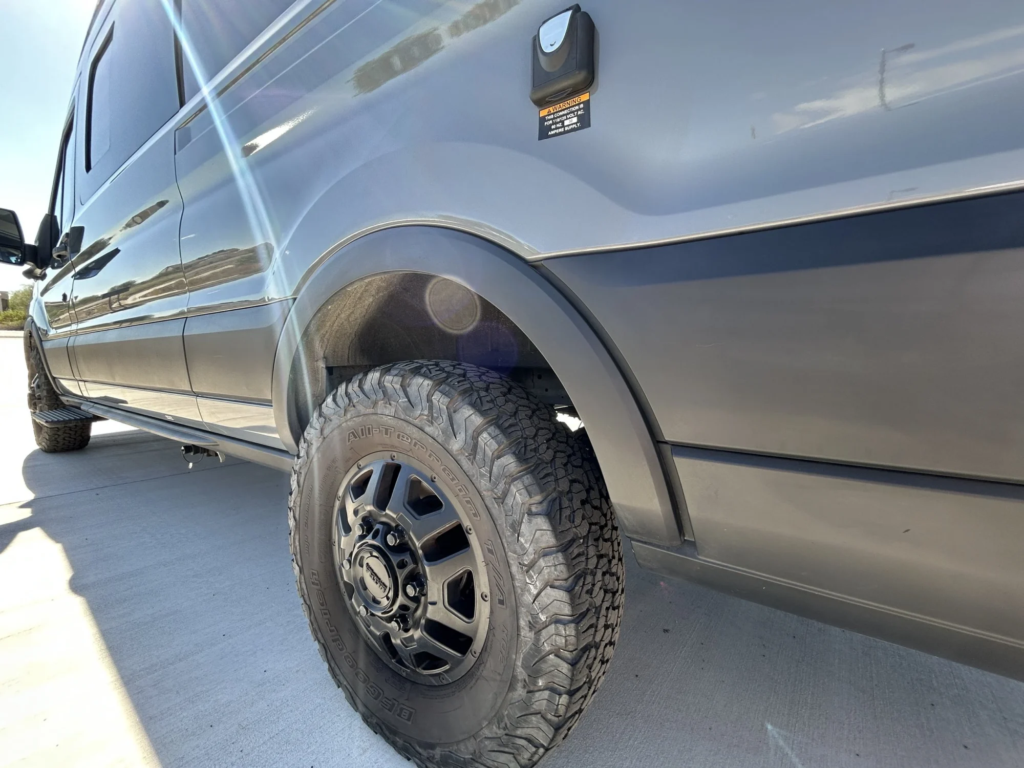 2024 Ford Transit 350 148 High Roof AWD, rear driver-side quarter panel showing 30A shore power inlet and Ultra Hunter wheel with KO2 tire
