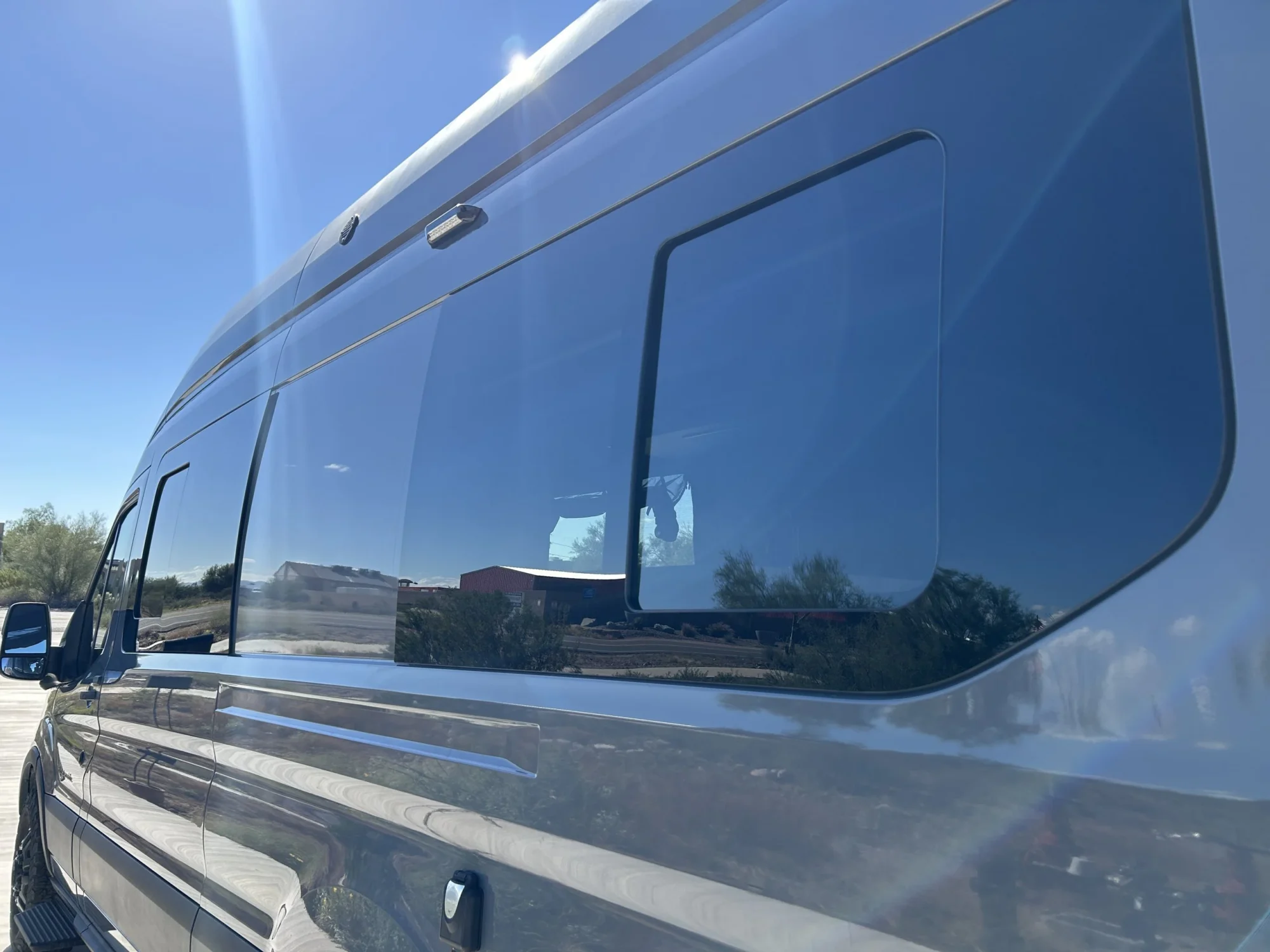 2024 Ford Transit 350 148 High Roof AWD, driver-side exterior showing three full-size slider windows and Abyss Gray paint