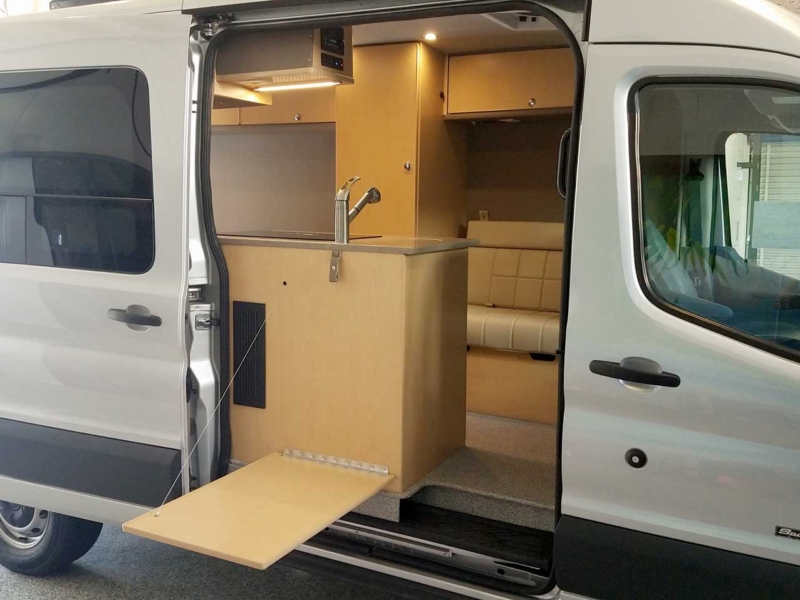 Inside a custom silver Sportsmobile Transit conversion van with a longer galley.