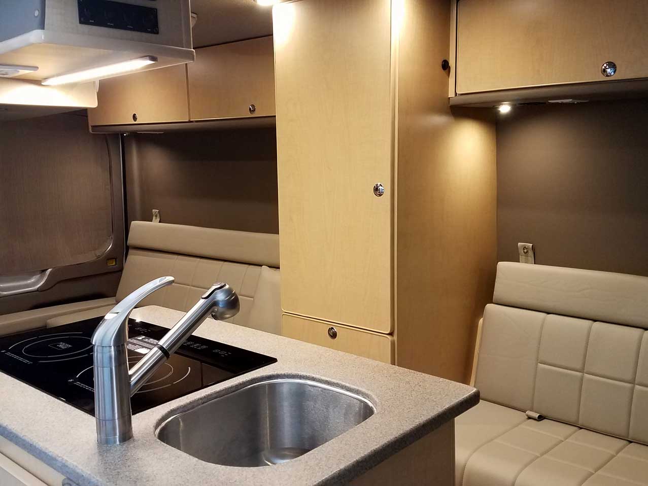 Inside a custom silver Sportsmobile Transit conversion van with low cabinets for plenty of room.