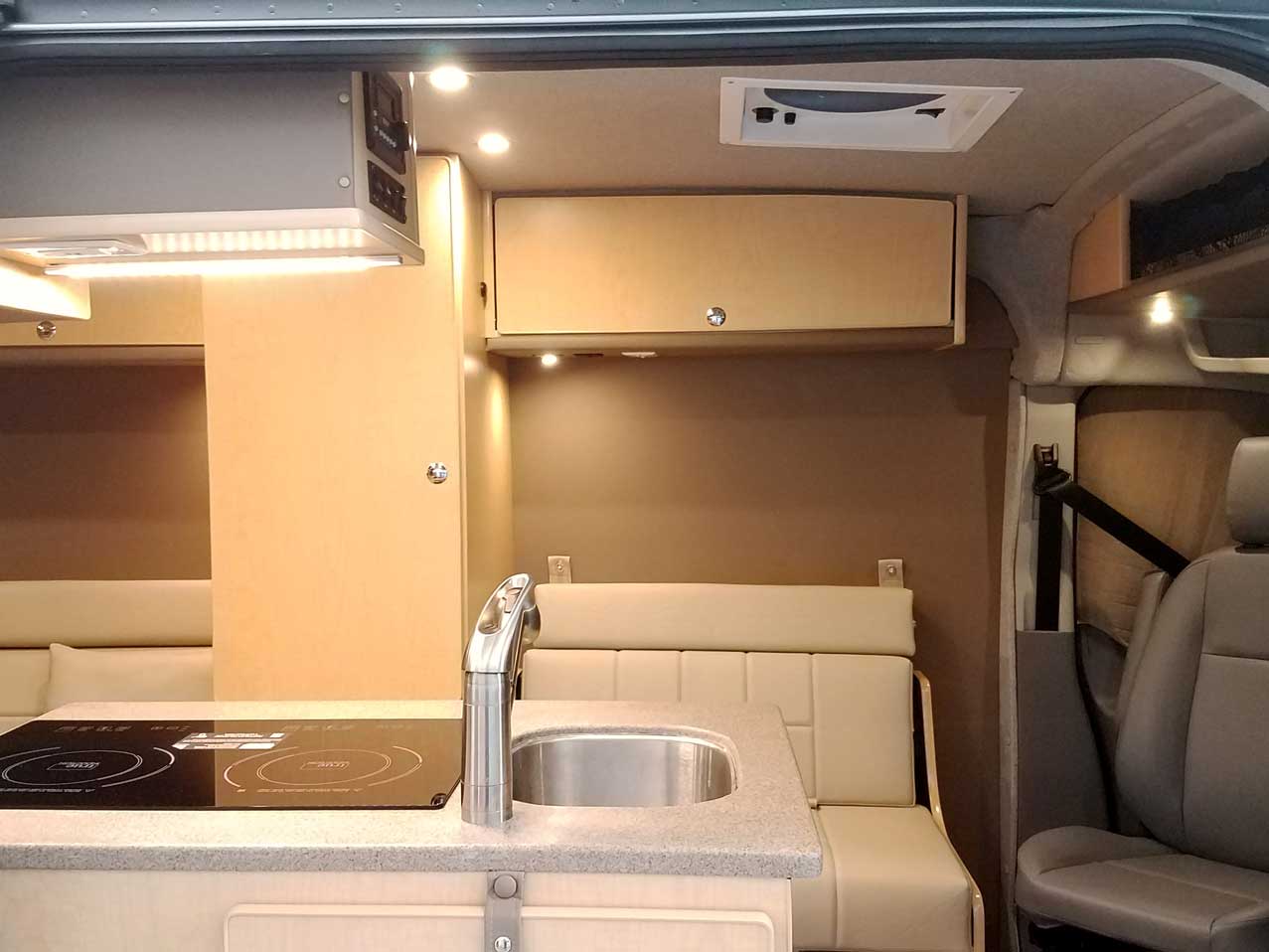 Inside a custom silver Sportsmobile Transit conversion van with plenty of seating for seven people.