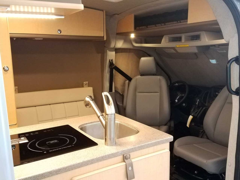 Inside a custom silver Sportsmobile Transit conversion van with a flip up counter top extension.