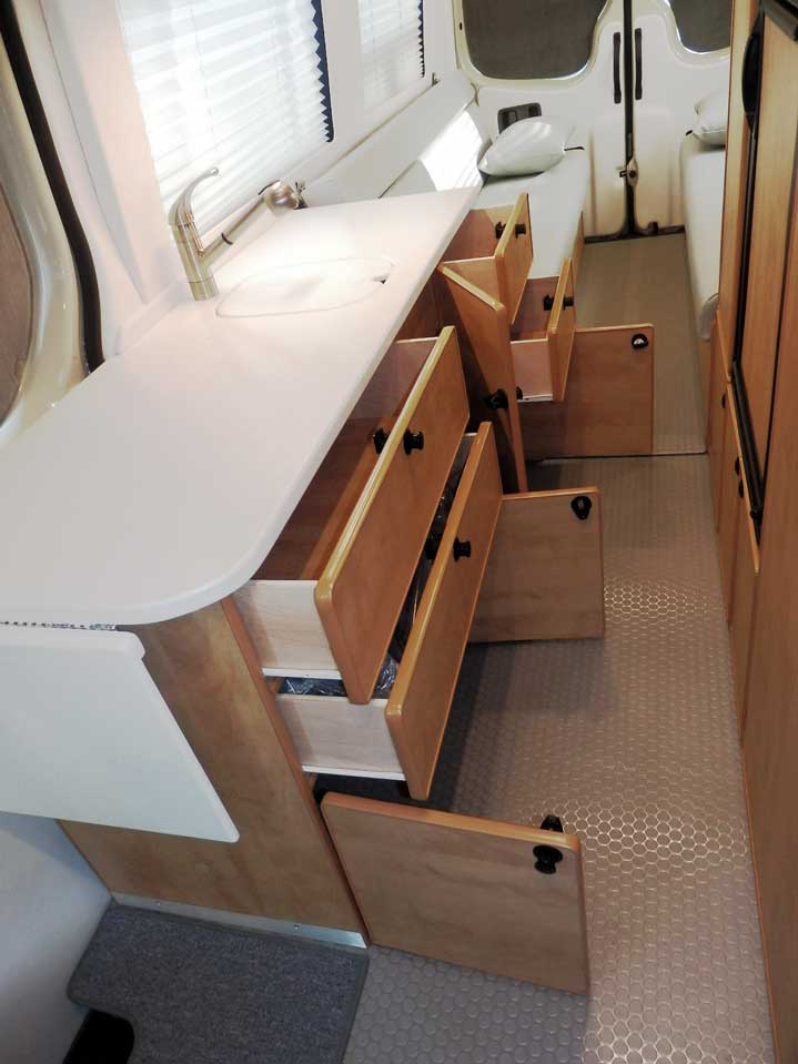 Plenty of storage space and cabinets in a Ford Transit camper conversion.