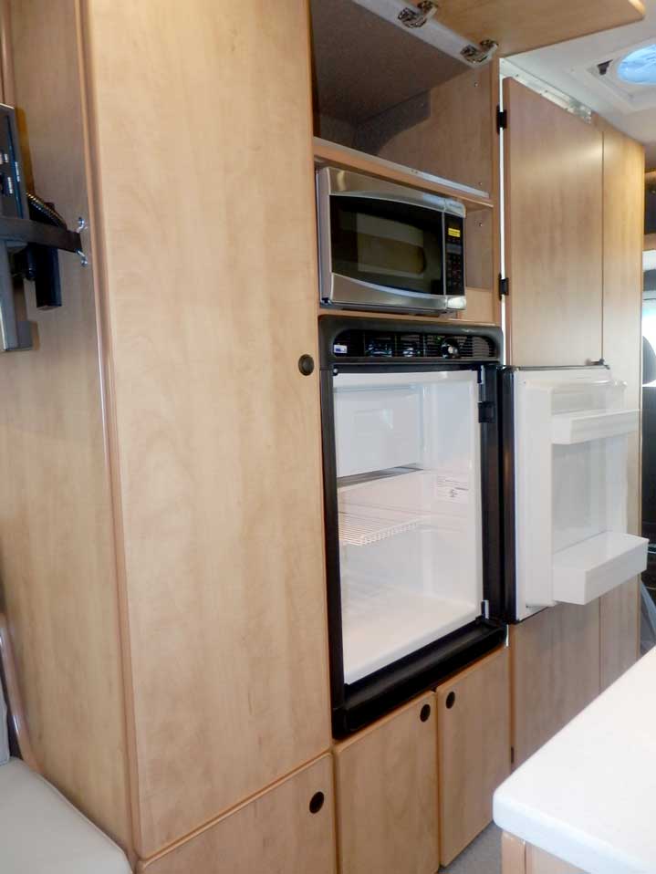 Ford Transit camper conversion featuring a microwave and refrigerator in the galley.
