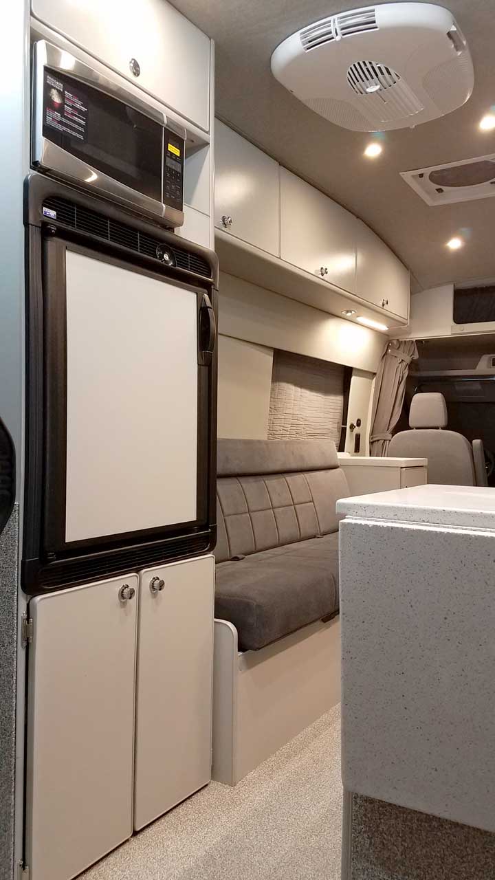 Interior view of a Sportsmobile Transit van conversion with a large refrigerator.