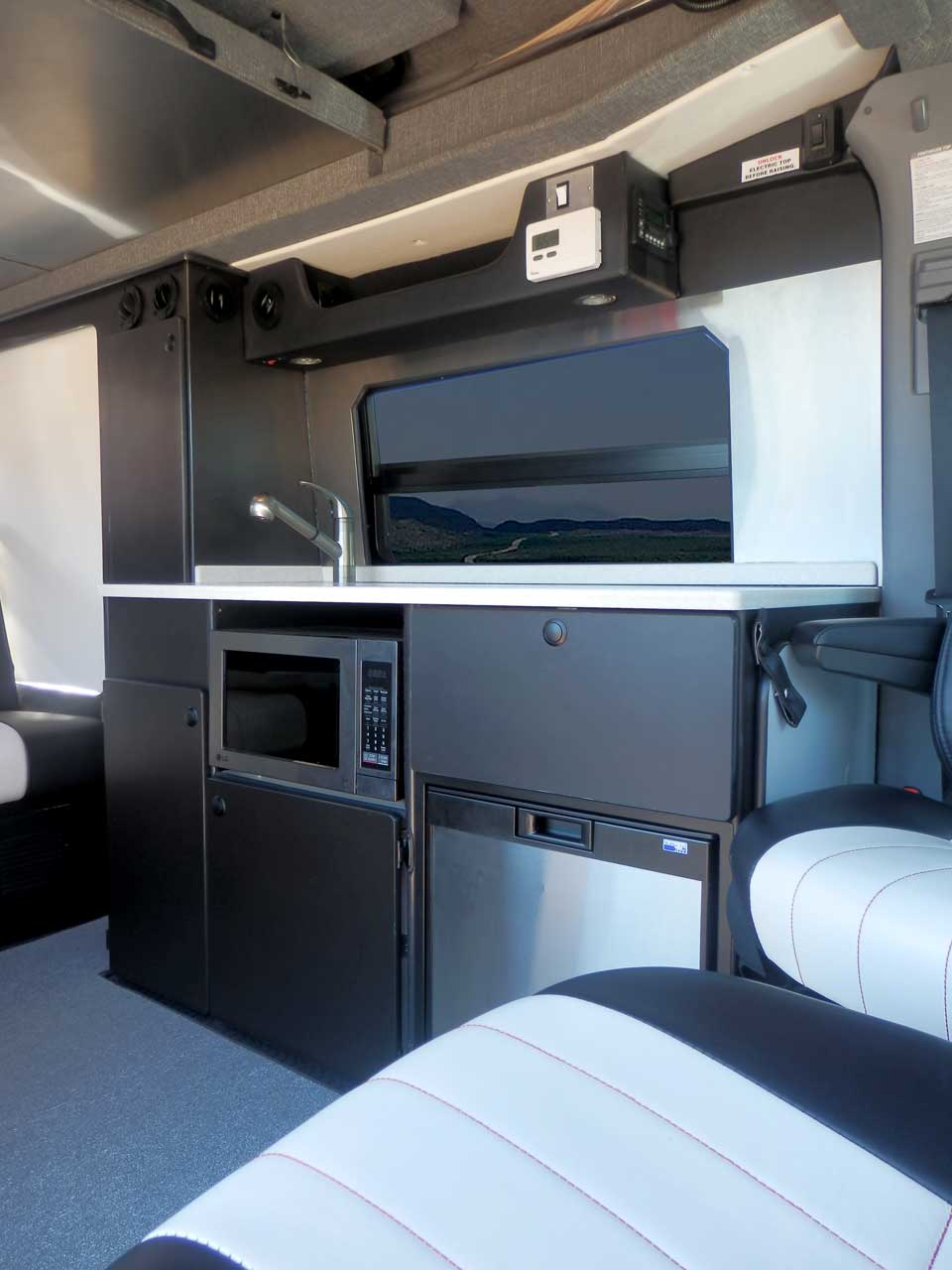 Sportsmobile camper van converison with black cabinets in the galley.
