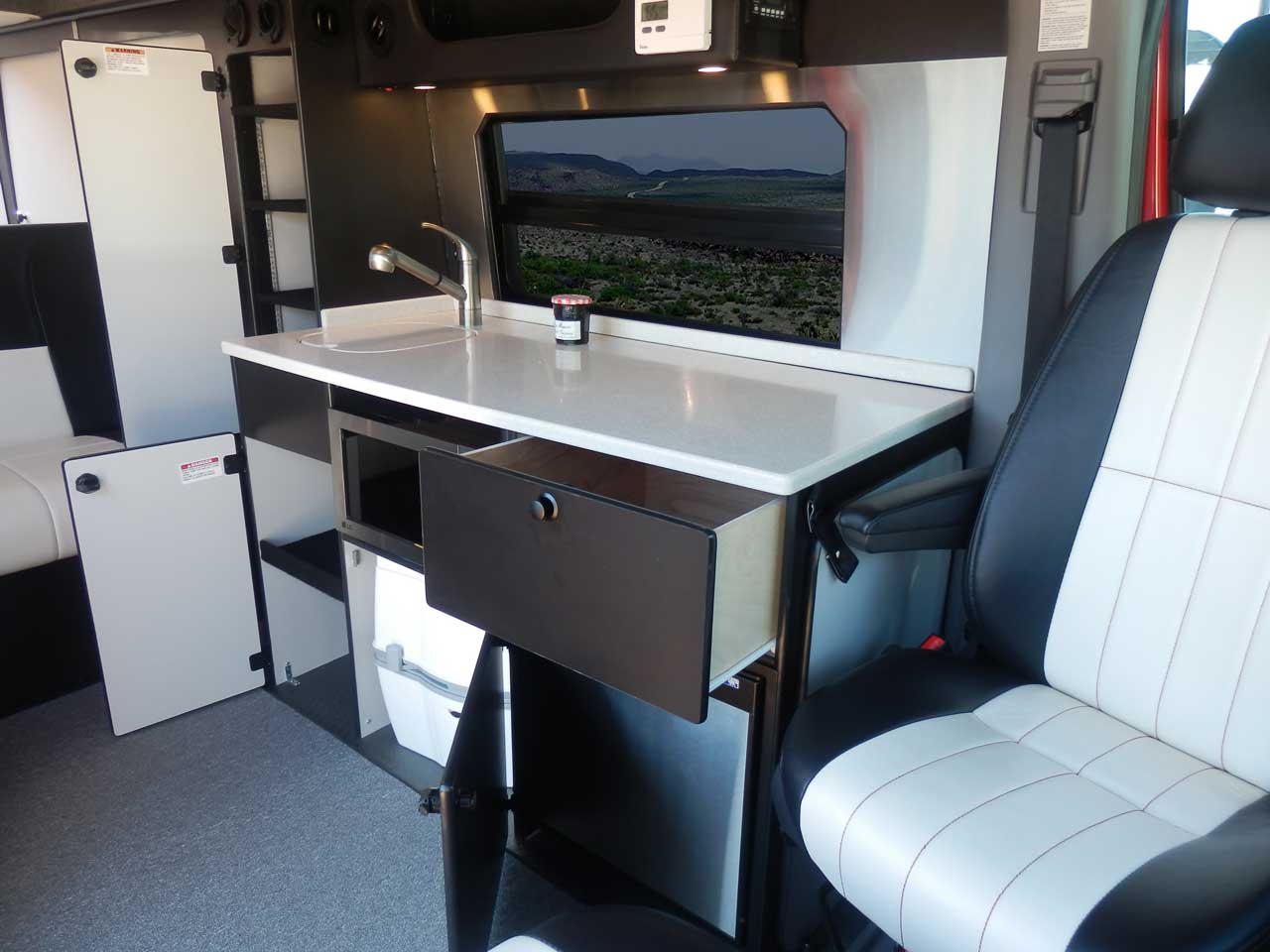 Sportsmobile camper van conversion with cabinets that feature doors and drawers.